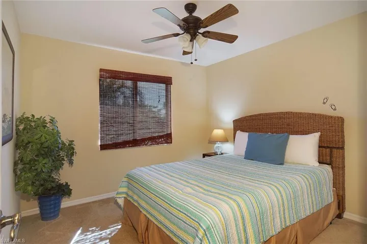 Bedroom featuring light colored carpet, baseboards, and a ceiling fan