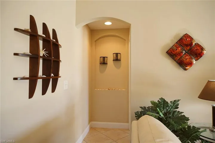 Hall featuring light tile patterned floors, baseboards, and arched walkways