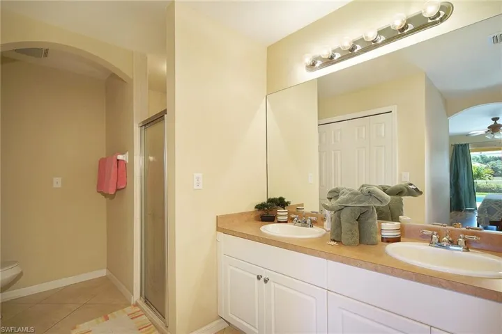 Bathroom with a sink, tile patterned flooring, a shower stall, and a ceiling fan
