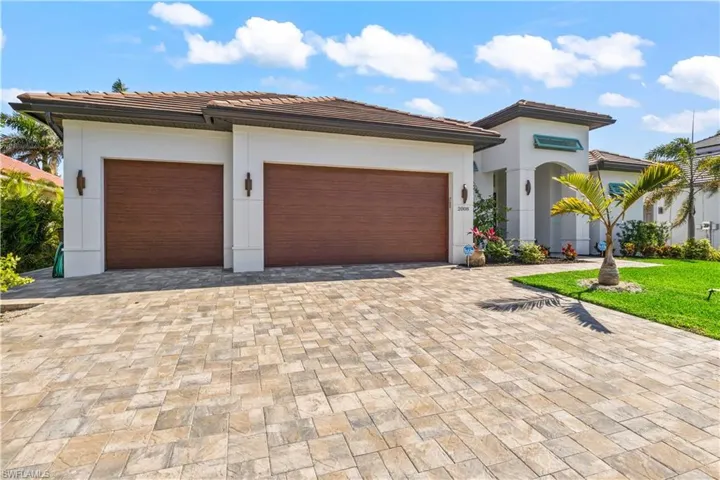 Close up view of the front of home with hurricane impact doors, windows and garage doors as well as a long driveway that is paved!