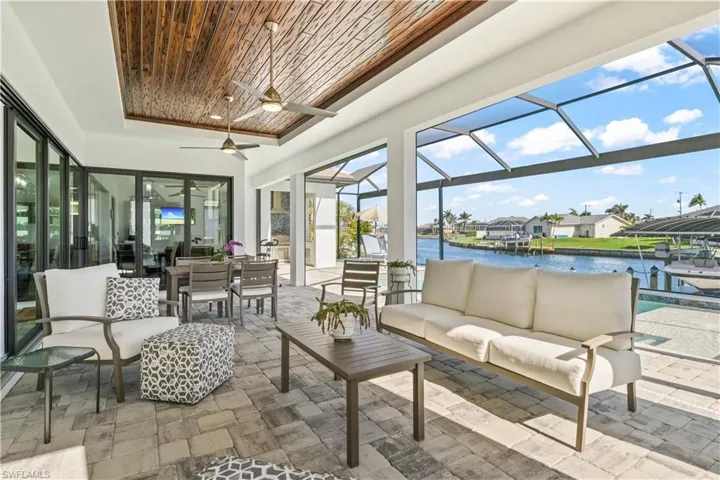 Another great feature of this home is the multiple outdoor living spaces - this is a large sitting and dining area under shade with cypress wood accents and hurriicane rated electronic roll down screens for both shade and protection!