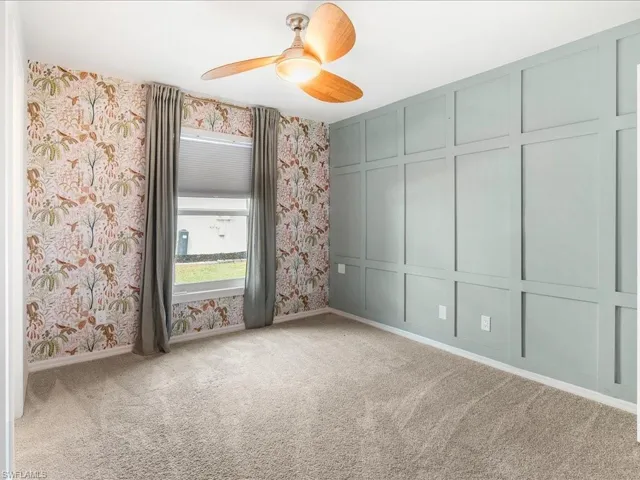 Second bedroom featuring carpet flooring, baseboards, wallpapered wall, ceiling fan, and a decorative wall