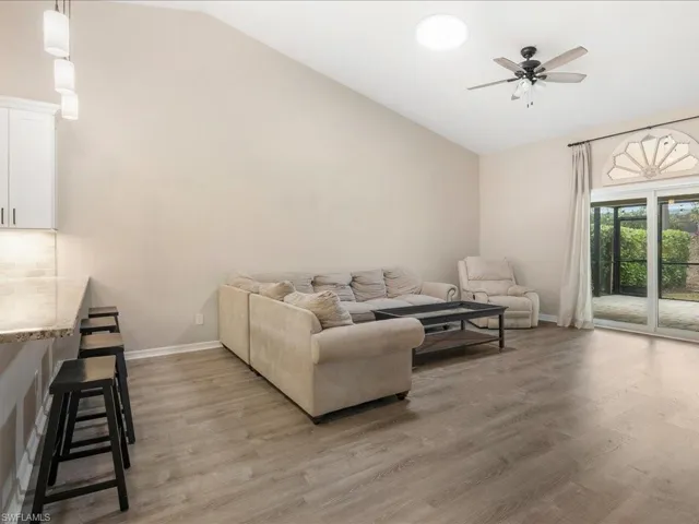Living area featuring baseboards, lofted ceiling, ceiling fan, and light wood-style floors