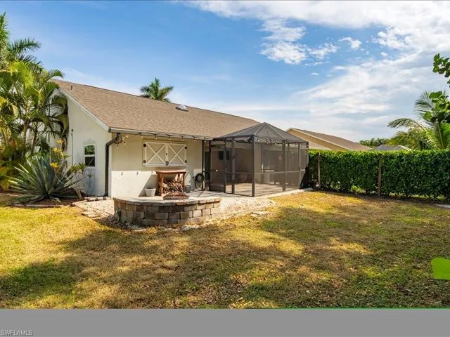 Back of property featuring a lanai, a paver patio, a fire pit, and a private yard