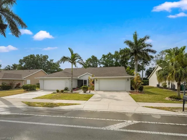 View of front of house with stucco siding, a front yard, driveway, and a garage