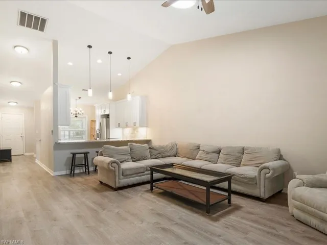 Spacious Living area with high vaulted ceiling, light wood finished floors, baseboards, ceiling fan