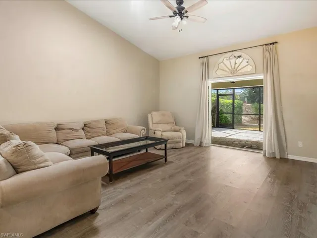 Living room featuring baseboards, ceiling fan, wood finished floors, and vaulted ceiling