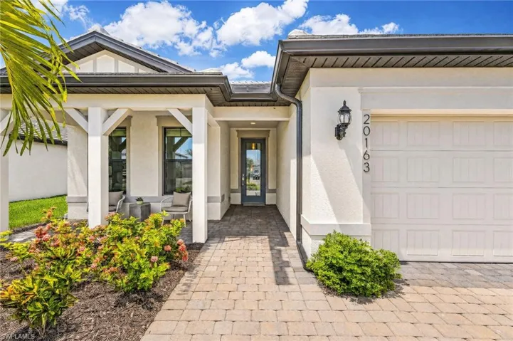 Stucco exterior with a paver walkway, columned entry, and a covered front porch