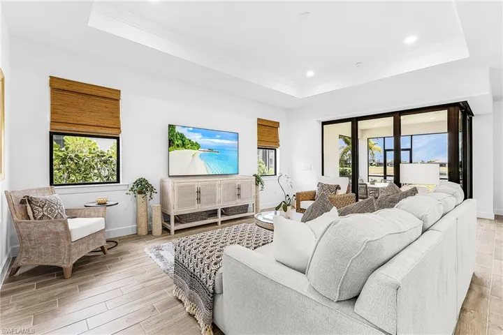 Open-concept living space with wood-finish flooring, tray ceiling, and recessed lighting