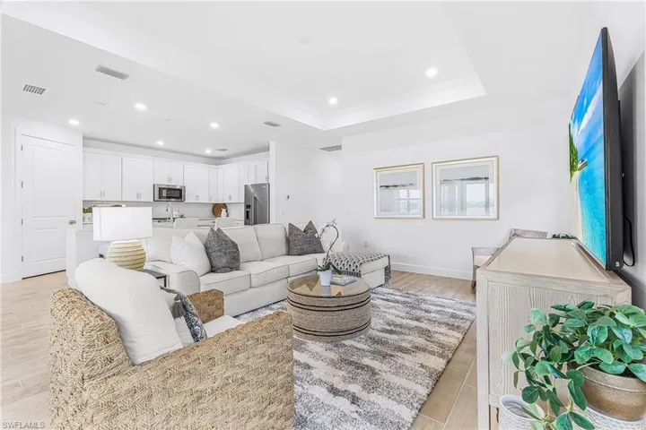 Open-concept living space featuring wood-finish tile flooring, recessed lighting, and a tray ceiling