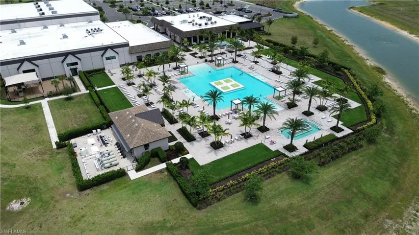 Expansive aquatic amenity featuring multiple pools, surrounding paver decking, and mature palm trees