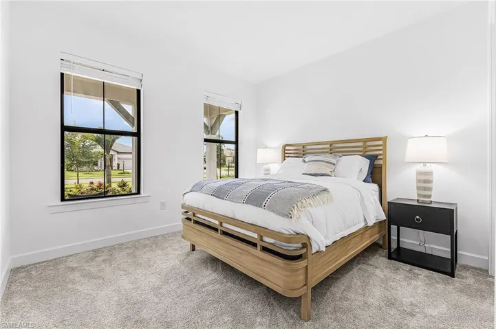 Bright room featuring two large windows with black framing, white walls, and light-colored carpeting