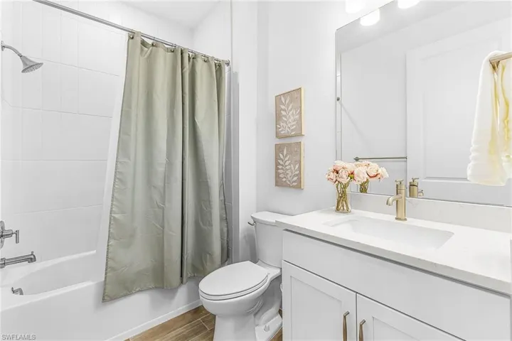 Full bathroom featuring a white vanity with an integrated sink, a large mirror, and a toilet