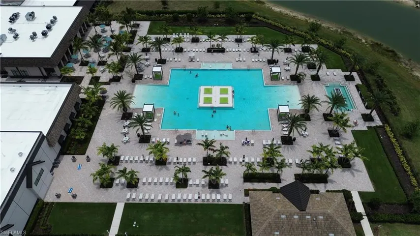 Expansive resort-style pool area featuring a large main pool with an island platform, an additional rectangular pool, and ample surrounding deck space