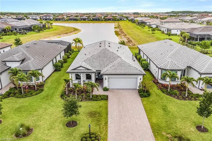 Single-story residence featuring a tile roof, paver driveway, an attached garage, and a covered entry porch with columns