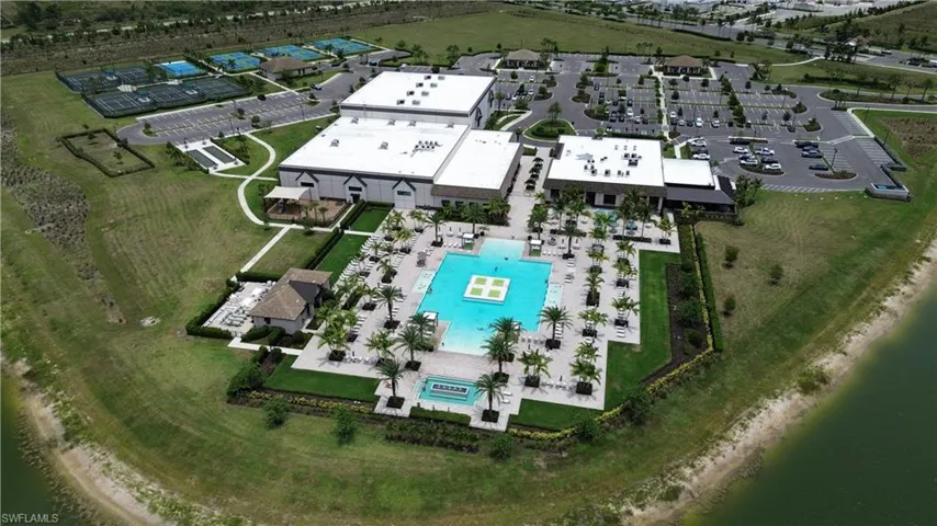 Expansive recreational complex featuring a large swimming pool, surrounding patio with multiple lounge chairs, and numerous palm trees