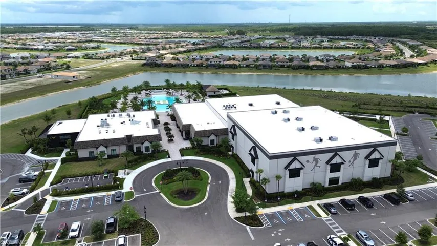 Expansive recreational facility featuring a large pool area, multiple buildings with architectural detailing, surrounding roadways, and structured parking areas