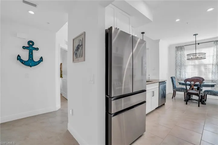 Kitchen with appliances with stainless steel finishes, white cabinetry, and light tile flooring