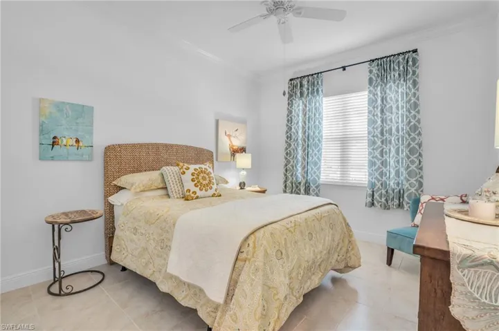Tiled bedroom with crown molding and ceiling fan
