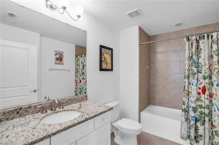 Full bathroom with shower / bath combination with curtain, vanity, and toilet
