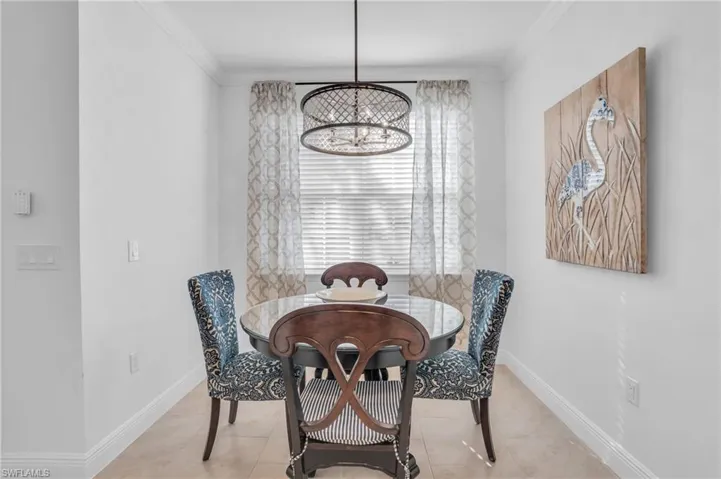 Tiled dining room featuring ornamental molding and a chandelier