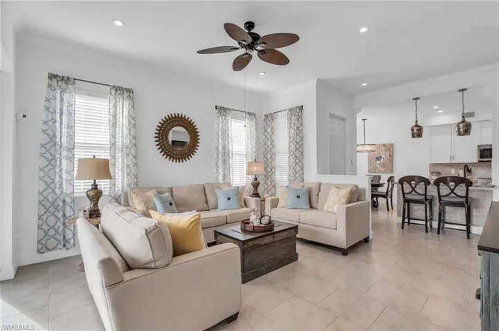 Tiled living room with a wealth of natural light, ornamental molding, and ceiling fan