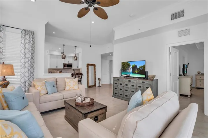 Tiled living room with ornamental molding and ceiling fan