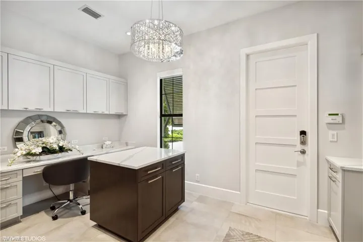 Tiled office featuring built in desk and a chandelier