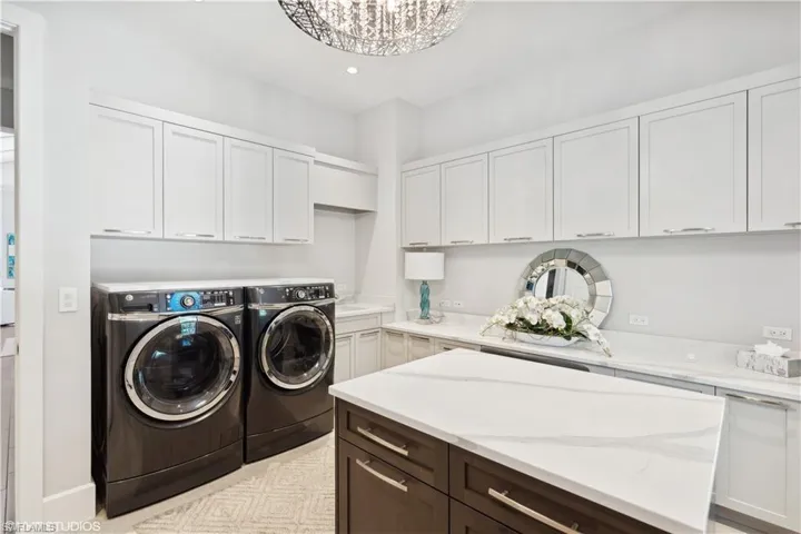 Washroom featuring independent washer and dryer, a chandelier, and cabinets