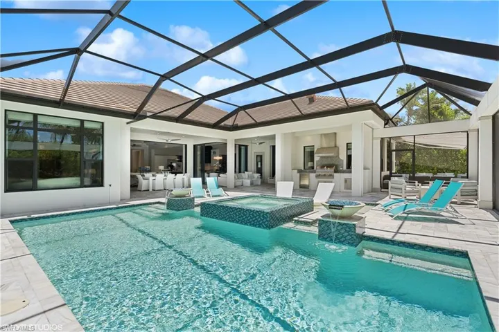 View of swimming pool with glass enclosure, an in ground hot tub, ceiling fan, a patio, and an outdoor hangout area