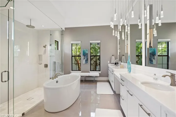 Bathroom with tile flooring, ornamental molding, shower with separate bathtub, large vanity, and dual sinks
