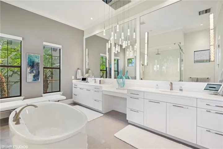 Bathroom featuring dual bowl vanity, tile flooring, crown molding, and a wealth of natural light