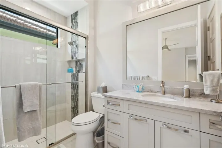 Bathroom featuring an enclosed shower, toilet, and oversized vanity