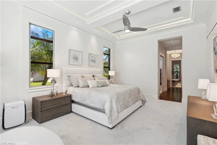 Bedroom featuring light colored carpet, ceiling fan, a raised ceiling, and crown molding