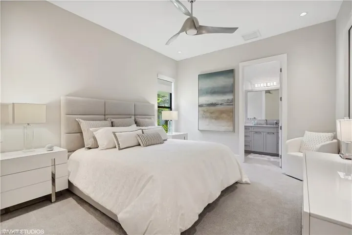 Carpeted bedroom with sink, connected bathroom, and ceiling fan