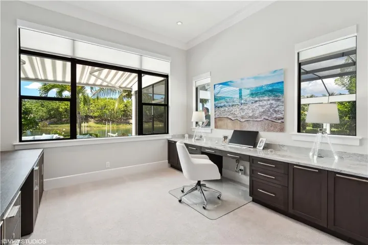 Carpeted office featuring built in desk, crown molding, and plenty of natural light