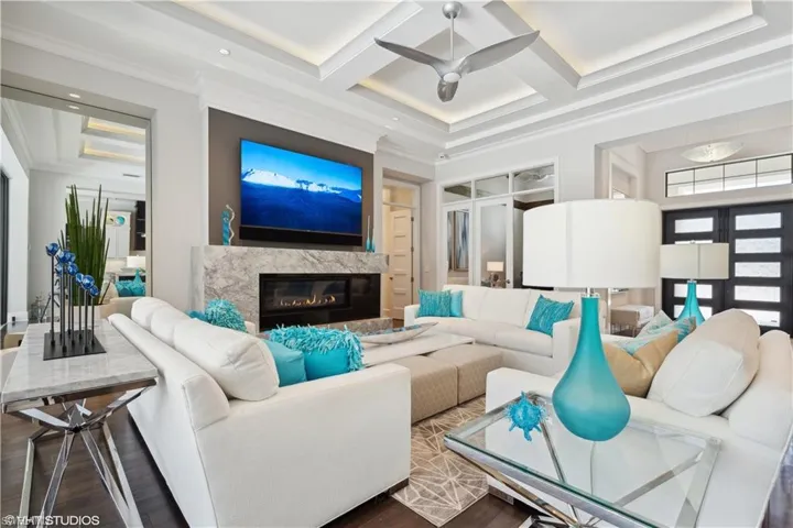 Living room with crown molding, a high end fireplace, hardwood / wood-style floors, coffered ceiling, and ceiling fan