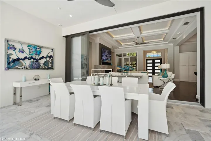 Tiled dining area with coffered ceiling, ceiling fan, and beam ceiling