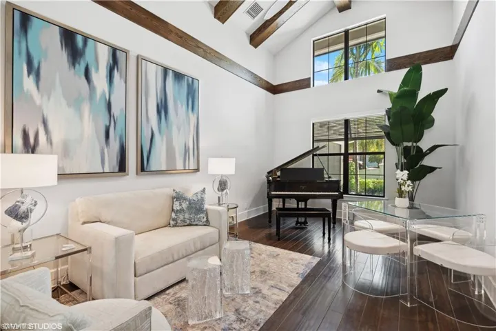 Living room featuring high vaulted ceiling, beam ceiling, and hardwood / wood-style floors