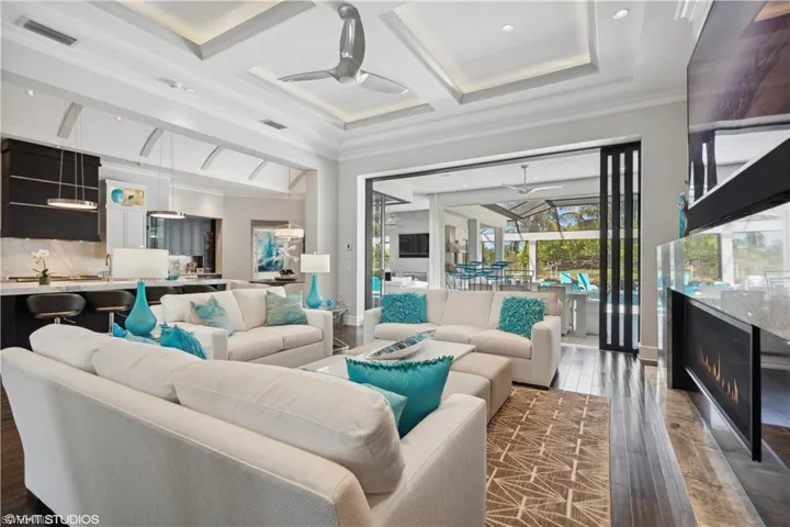 Living room featuring crown molding, coffered ceiling, ceiling fan, and dark hardwood / wood-style flooring