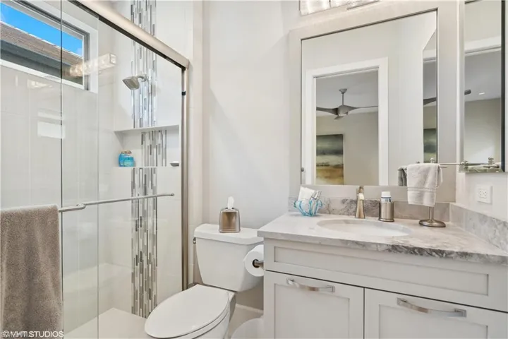 Bathroom featuring vanity with extensive cabinet space, an enclosed shower, and toilet