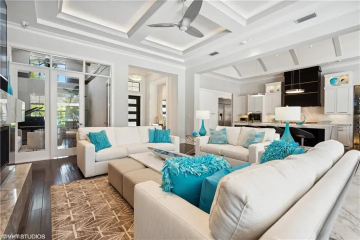 Living room with coffered ceiling, ceiling fan, crown molding, hardwood / wood-style floors, and beam ceiling
