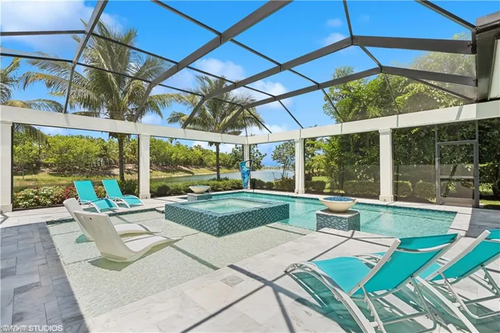 View of swimming pool with a patio, glass enclosure, and an in ground hot tub