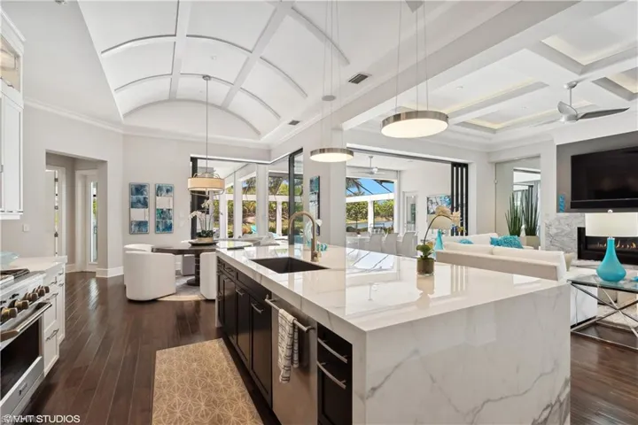 Kitchen with white cabinetry, a center island with sink, dark hardwood / wood-style flooring, high end stainless steel range oven, and sink