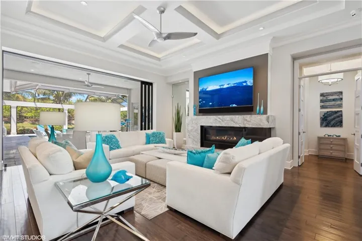 Living room featuring hardwood / wood-style flooring, a fireplace, ceiling fan, and coffered ceiling