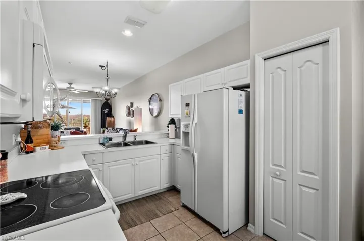 Kitchen featuring kitchen peninsula, white appliances, sink, and hanging light fixtures