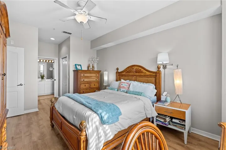Bedroom featuring a closet, ensuite bathroom, light hardwood / wood-style flooring, and ceiling fan