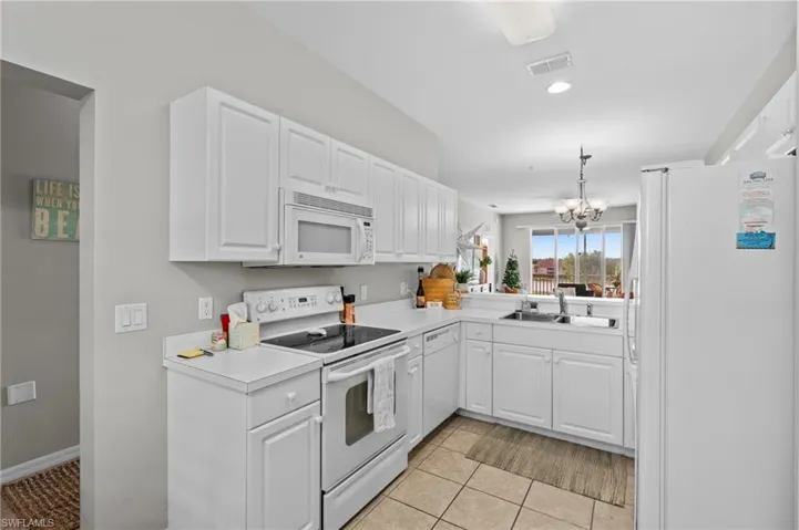 Kitchen featuring sink, white cabinets, a chandelier, white appliances, and light tile patterned flooring