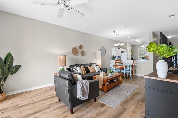 Living room with light hardwood / wood-style flooring and ceiling fan with notable chandelier