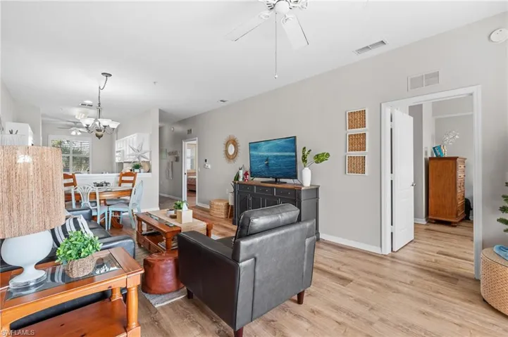 Living room featuring ceiling fan with notable chandelier and light hardwood / wood-style flooring